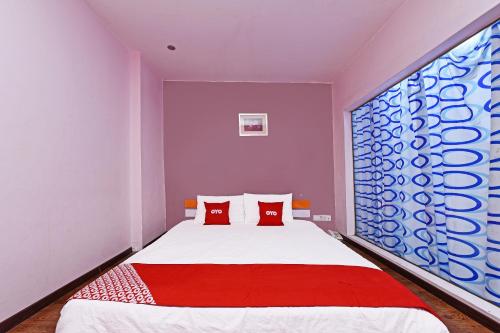 1 dormitorio con 1 cama grande con almohadas rojas en Super OYO 992 Orange Hotel Kuala Pilah, en Kuala Pilah