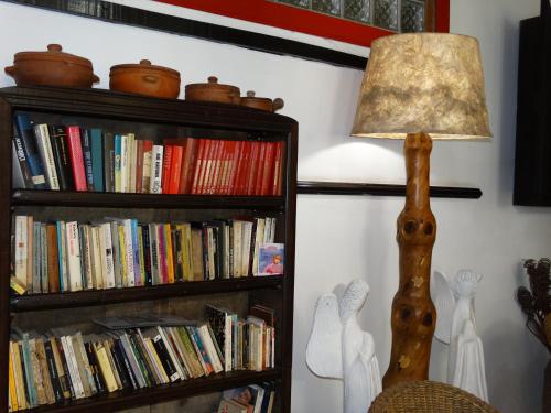a lamp sitting next to a book shelf with books at Pousada Estalagem do Porto in Arraial do Cabo