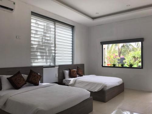 1 Schlafzimmer mit 2 Betten und einem Fenster in der Unterkunft Green Star Premium Resort - Mui Ne - Formerly Hung Thinh Resort in Ấp Long Sơn