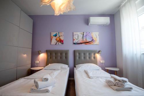 two beds in a room with purple walls at Villa Lumaka Sun - Amazing Home In Brodarica with 4 Bedrooms, Wifi, Outdoor Swimming Pool and Heated Swimming Pool in Brodarica