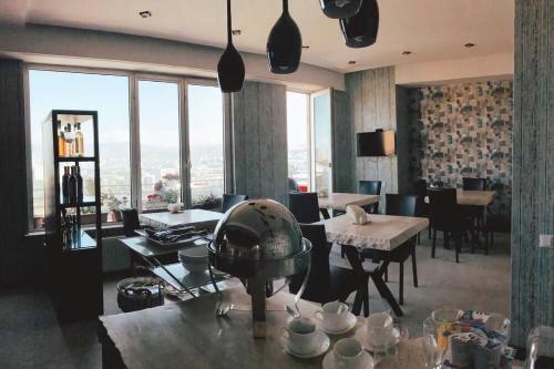 ein Esszimmer mit Tischen, Stühlen und Fenstern in der Unterkunft Panorama 360° Hotel in Tbilisi City
