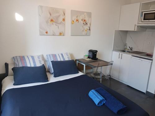 Cet appartement comprend une chambre avec un lit doté d'oreillers bleus et une cuisine. dans l'établissement Appartement Plein Ciel, à Nice