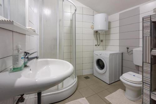 a bathroom with a sink and a washing machine at Apartman Franka in Crikvenica