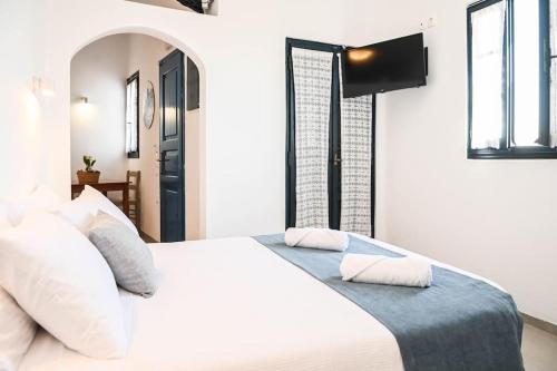 sypialnia z białym łóżkiem i telewizorem na ścianie w obiekcie Villa Solasta #2 with jacuzzi in Santorini w Akrotiri
