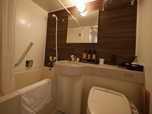 a bathroom with a sink and a toilet and a mirror at Hotel Route-Inn Tokyo Asagaya in Tokyo