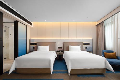 dos camas sentadas una al lado de la otra en una habitación en Hampton by Hilton Shenzhen North Station en Shenzhen