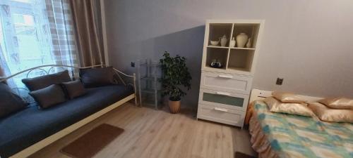a bedroom with a bed and a couch and a window at Hostel CION in Gliwice