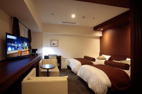 a hotel room with two beds and a flat screen tv at Hotel Plaza Osaka in Osaka