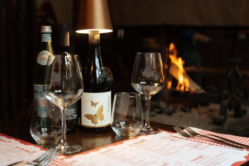 a table with three wine glasses and a fireplace at Al Fogolâr Rooms & Osteria with Saunaland in Tolmezzo