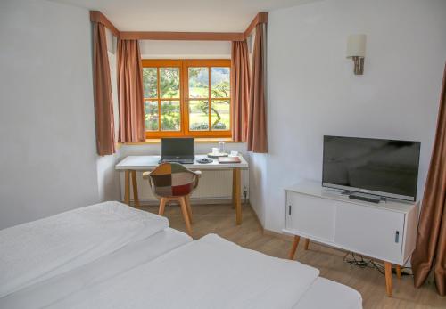 a bedroom with a desk and a tv and a bed at Hotel Sonnenhof - bed & breakfast & appartements in Innsbruck