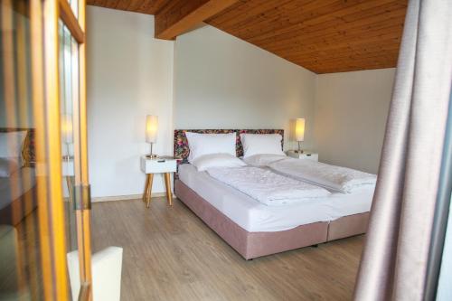 a bedroom with a white bed with a wooden ceiling at Hotel Sonnenhof - bed & breakfast & appartements in Innsbruck