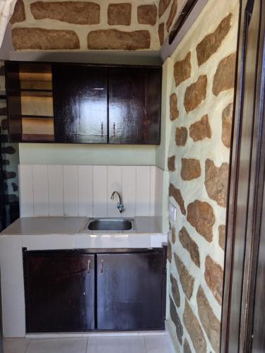 - une cuisine avec un évier et un mur en pierre dans l'établissement Home of Friends, à Kapchorwa
