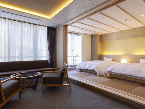 a hotel room with two beds and a couch at Ohashikan in Matsue
