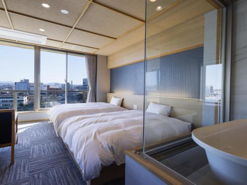 a bedroom with a large bed and a bath tub at Ohashikan in Matsue