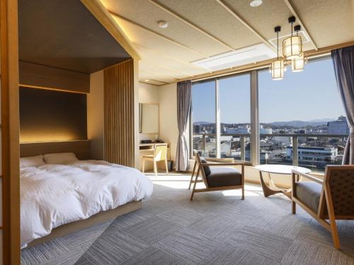 a bedroom with a bed and a desk and a large window at Ohashikan in Matsue