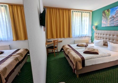 a hotel room with two beds and a table at Acron-Hotel Quedlinburg in Quedlinburg