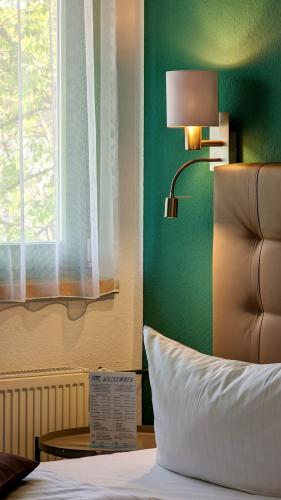 a bedroom with a green wall and a bed with a lamp at Acron-Hotel Quedlinburg in Quedlinburg