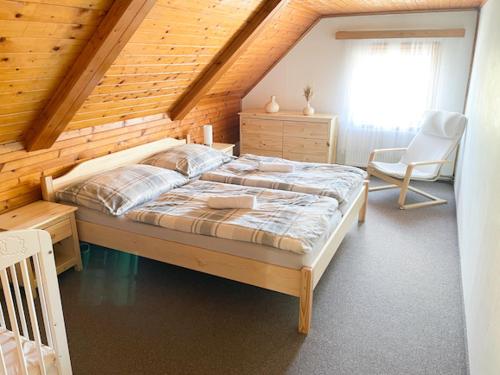 1 dormitorio con 1 cama grande y pared de madera en Chalupa Rozálka en Cerny Dul