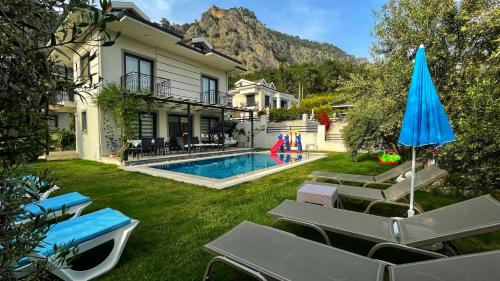 a house with a swimming pool with chairs and an umbrella at Private Villa in Gocek Villa Perest in Göcek