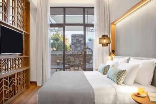 a hotel room with a bed and a large window at Mirabello Bay Luxury Resort in Agios Nikolaos