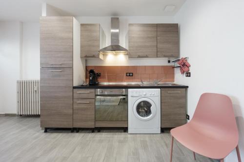 a kitchen with a washing machine and a pink chair at Romance O'Berry in Châteauroux