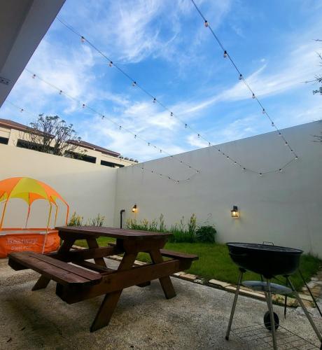 a picnic table and a grill with an umbrella at Olle Resort in Jeju