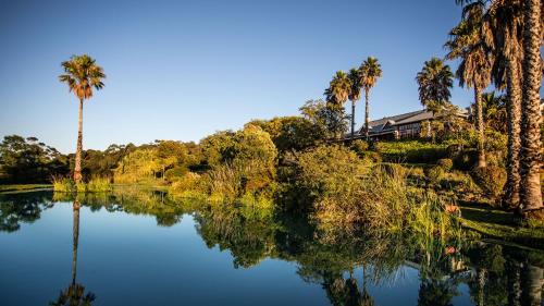 a house sitting on top of a lake with palm trees at The Caledon Hotel and Spa in Caledon
