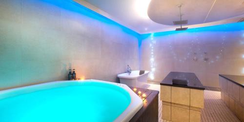 The Caledon Hotel and Spa في كاليدون: حمام مع حوض ومرحاض مع أضواء زرقاء