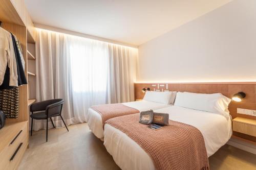 una habitación de hotel con 2 camas y una silla en ARTIEM Apartamentos, en Mahón
