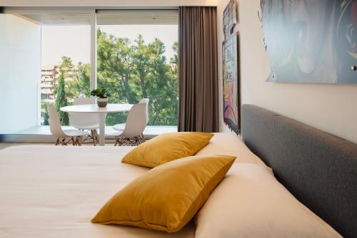 ein Schlafzimmer mit einem Bett mit gelben Kissen und einem Tisch in der Unterkunft Marina Gardens Boutique&Suites in Francavilla al Mare