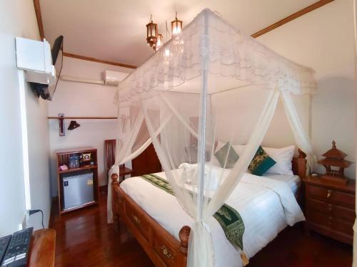 a bedroom with a canopy bed with white curtains at Aphilapa Residence in Chiang Mai