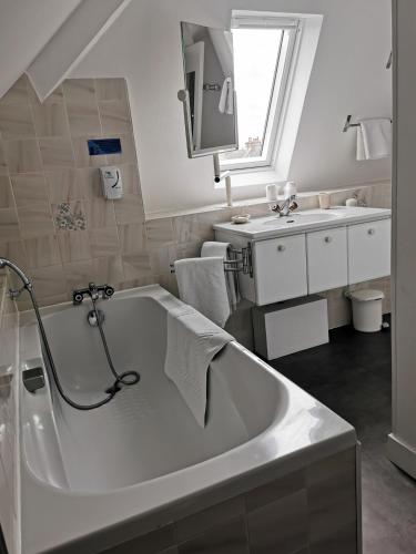 une salle de bain blanche avec une baignoire et un lavabo dans l'établissement La Granitiere Maison de Charme, à Saint-Vaast-la-Hougue