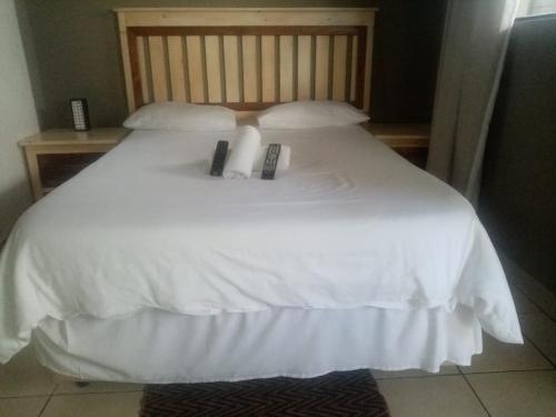 a white bed with two remote controls on it at Lisokhanya GuestHouse in East London