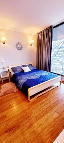 a bedroom with a bed with blue sheets and a window at HomeComfort Atlantic Room in Warsaw
