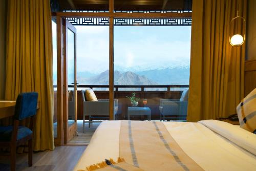 a bedroom with a large window with a view of mountains at Hotel Rewa Ladakh in Leh