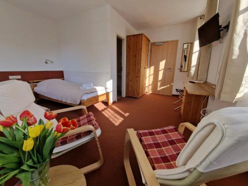 Garni Hotel Zum Hothertor في غورليتز: غرفة معيشة مع سرير وطاولة مع زهور