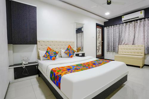 una camera da letto con un grande letto bianco con cuscini colorati di FabExpress Rajmahal a Navi Mumbai