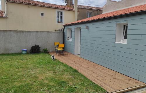a dog standing on a wooden deck next to a house at La Casita: Studio cosy indépendant de 25 m² in Les Sables-d'Olonne