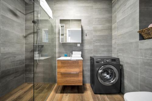 a bathroom with a washing machine and a shower at Kolska Grey Apartment in Warsaw