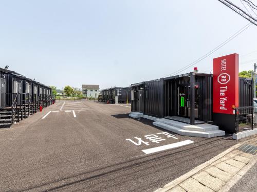 an empty parking lot with a row of shipping containers at HOTEL R9 The Yard Saito in Saito