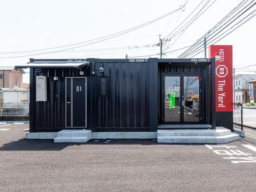 a black building with a door on a street at HOTEL R9 The Yard Saito in Saito