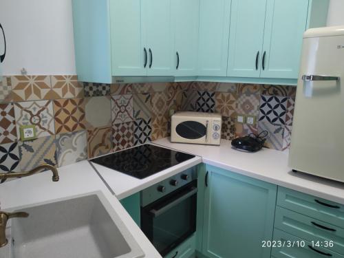 a kitchen with blue cabinets and a stove and a microwave at Harmony at Trifilianika in Trifilliánika