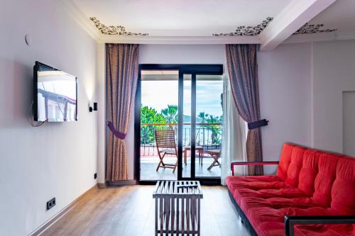 a living room with a red couch and a balcony at Costa Bitezhan Hotel - All Inclusive in Bitez