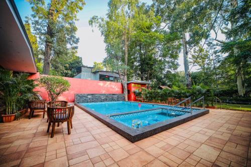 a swimming pool in a patio with a table and chairs at Hotel Malas in Panchgani
