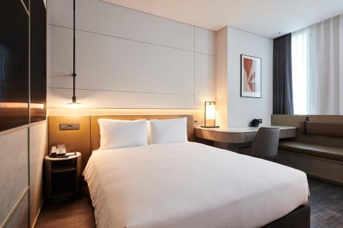 a hotel room with a large bed and a chair at Nine Tree Premier ROKAUS Hotel Seoul Yongsan in Seoul