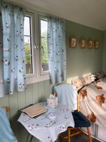 a room with a table and a bed and a window at Bells Meadow Shepherds Hut in Kings Lynn