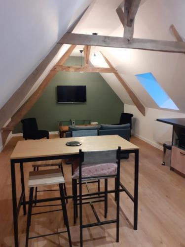 a room with a table and chairs in a attic at B&B - La Cense du Pont in Bachy