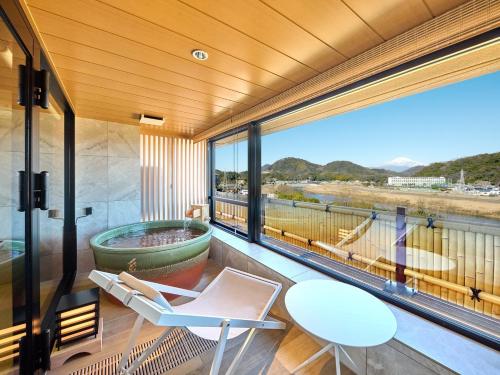 a balcony with a tub and a table and chairs at Fugaku Hanabusa in Izunokuni