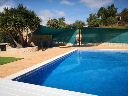 a swimming pool with a tent and a palm tree at Casa Camé in São Bartolomeu de Messines