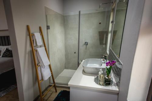 a white bathroom with a sink and a shower at Maya Manor in Hoedspruit